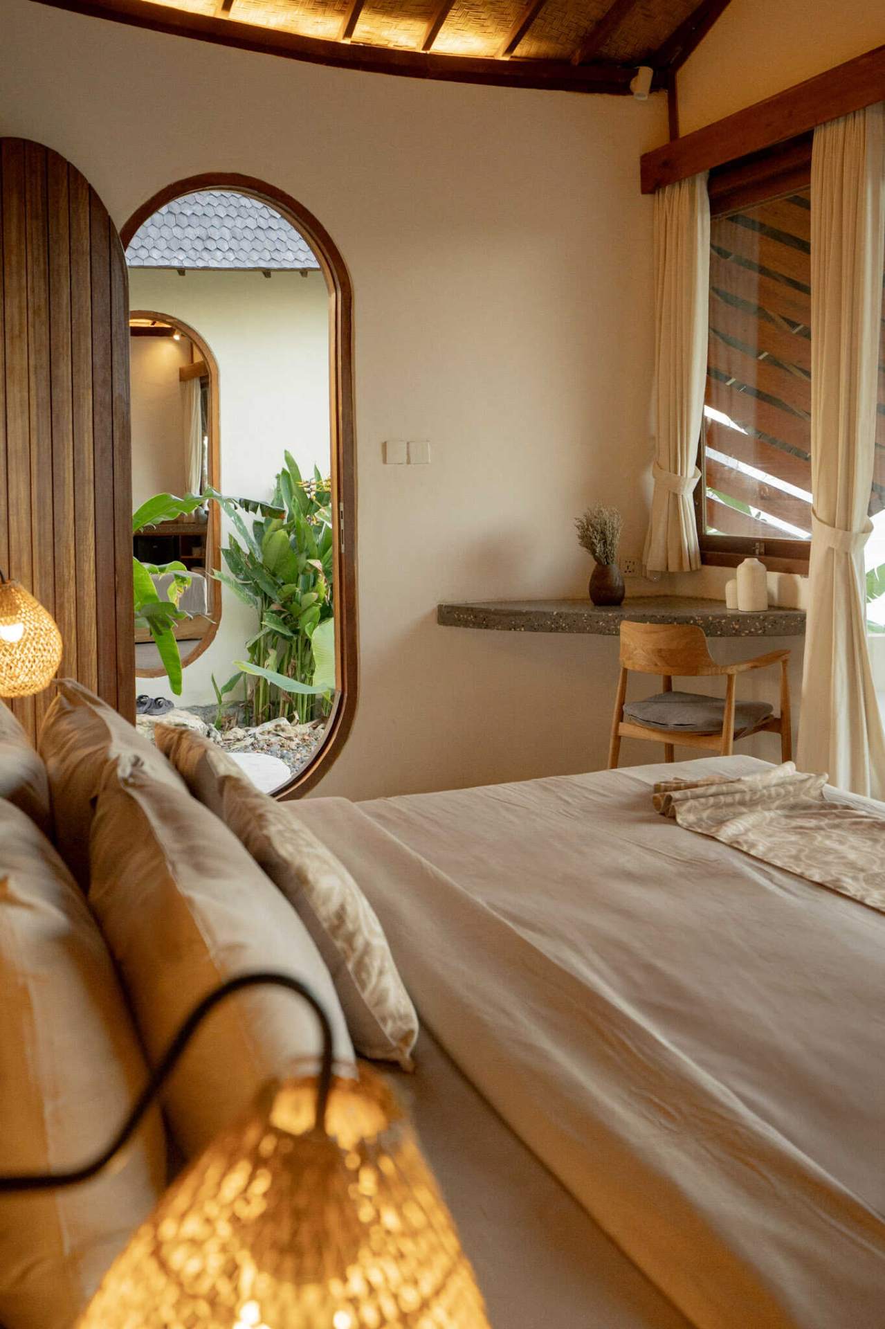 Tropical garden path lined with banana leaves and white flowers outside Elysian Cove accommodation in Sumbawa.