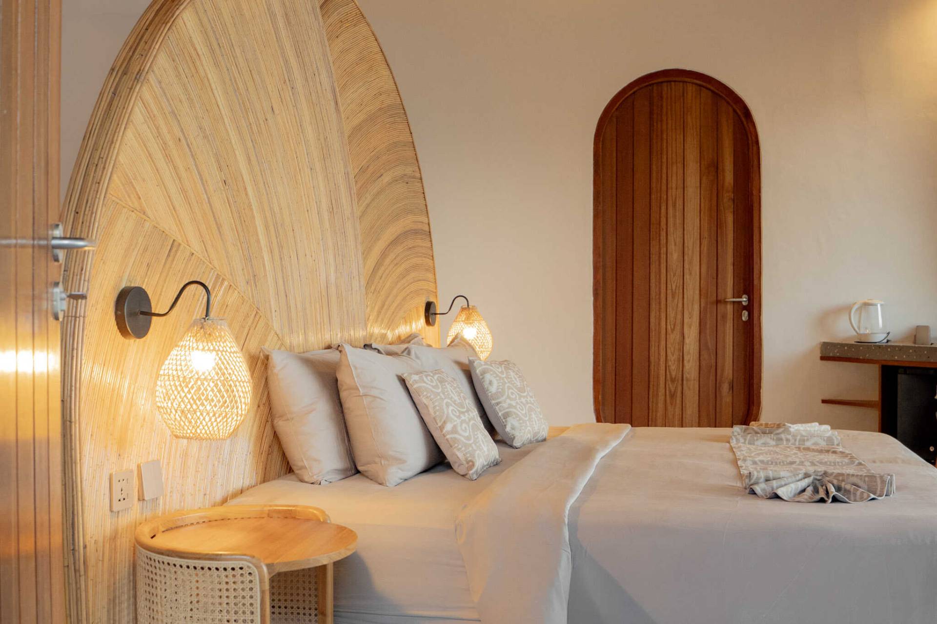 Cosy bedroom with soft lighting and natural textures at Elysian Cove, a boutique hotel in Sumbawa near the beach.